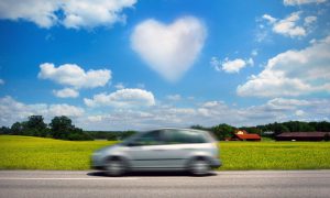 Bil på landsväg med hjärtformat moln på himlen