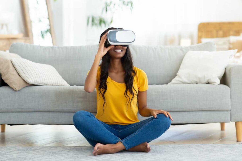 En kvinna med VR-glasögon sitter på golvet framför en soffa