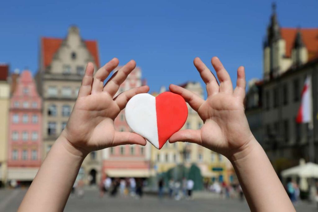 Ett barn håller upp ett hjärta i polska flaggans färger